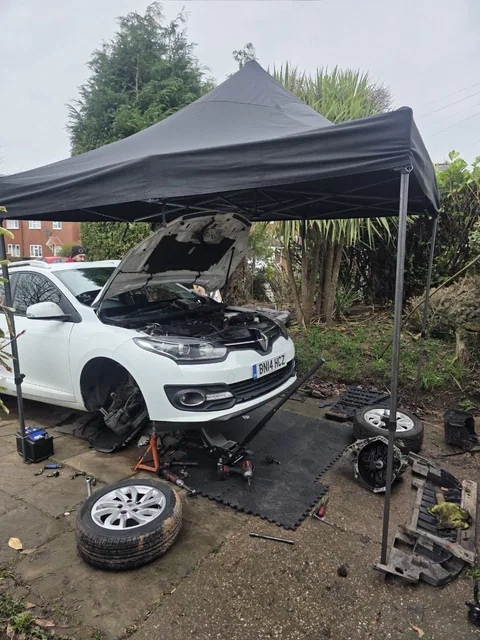 Atelier mobil instalat sub cort, pentru repararea unui Renault în curtea clientului